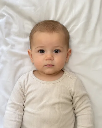 Photo de départ prise par un parent : bébé allongé sur un drap blanc, yeux ouverts